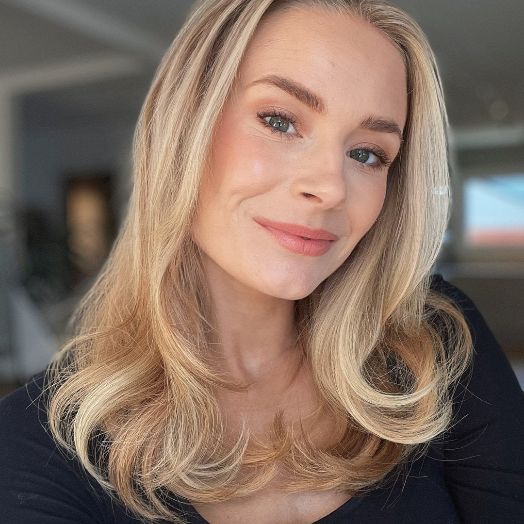 A smiling woman with long blonde hair in black top.