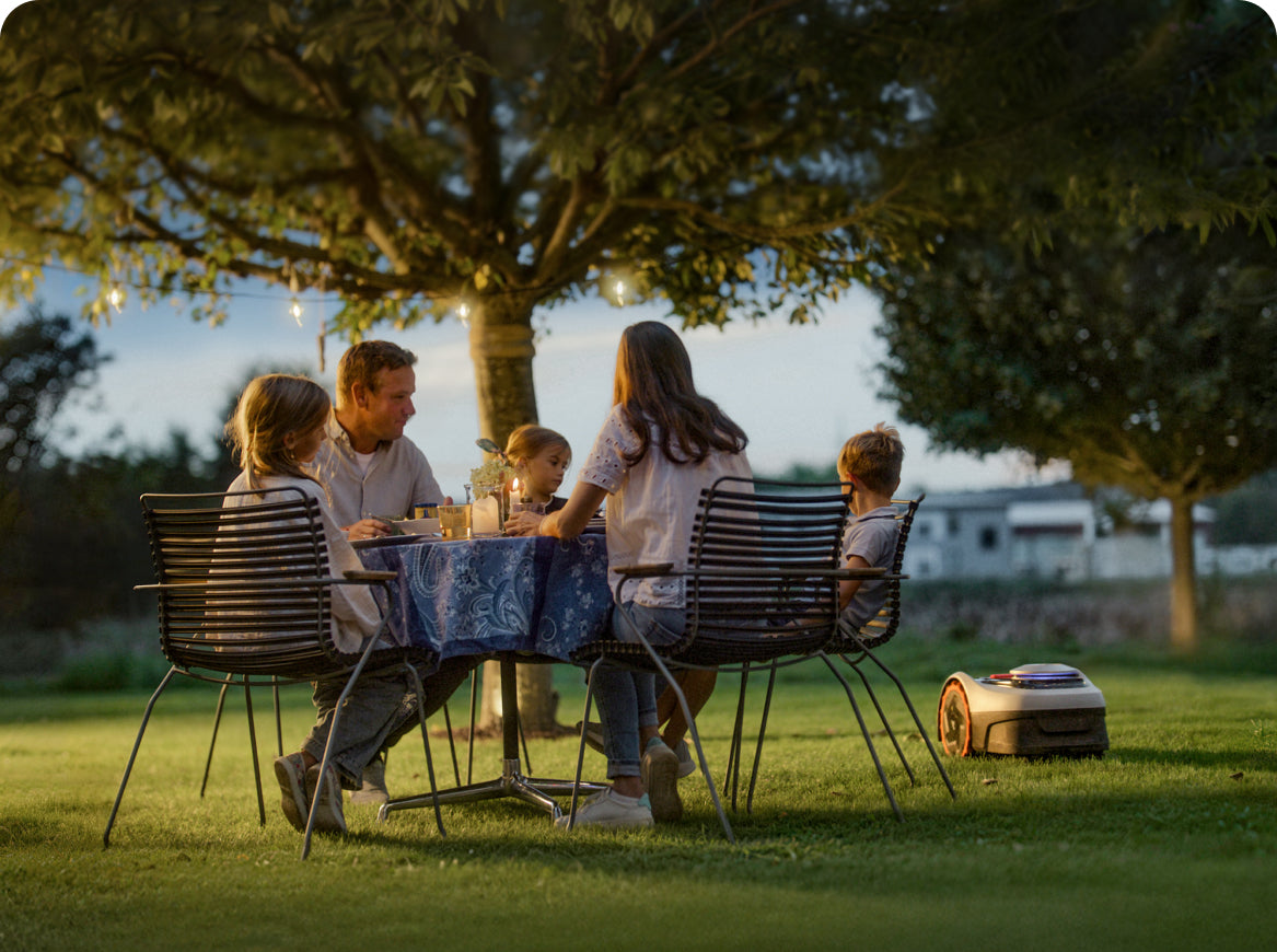 Navimow i110N robot lawn mower works while a family eats.
