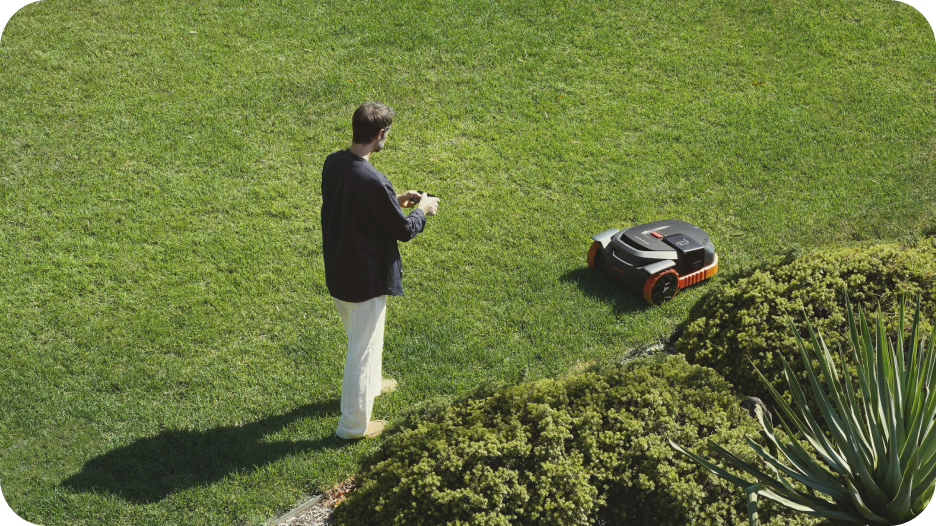 A man watches the Navimow i110N robot lawn mower working.