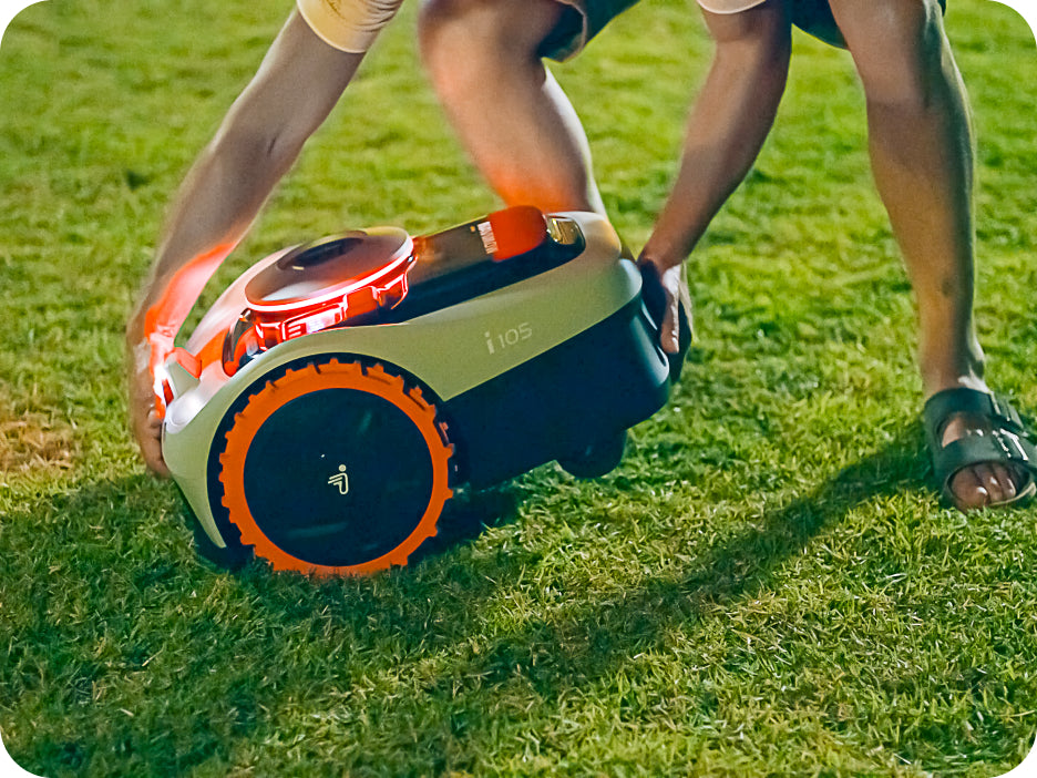 Navimow i105 robot lawn mower being held above the grass.