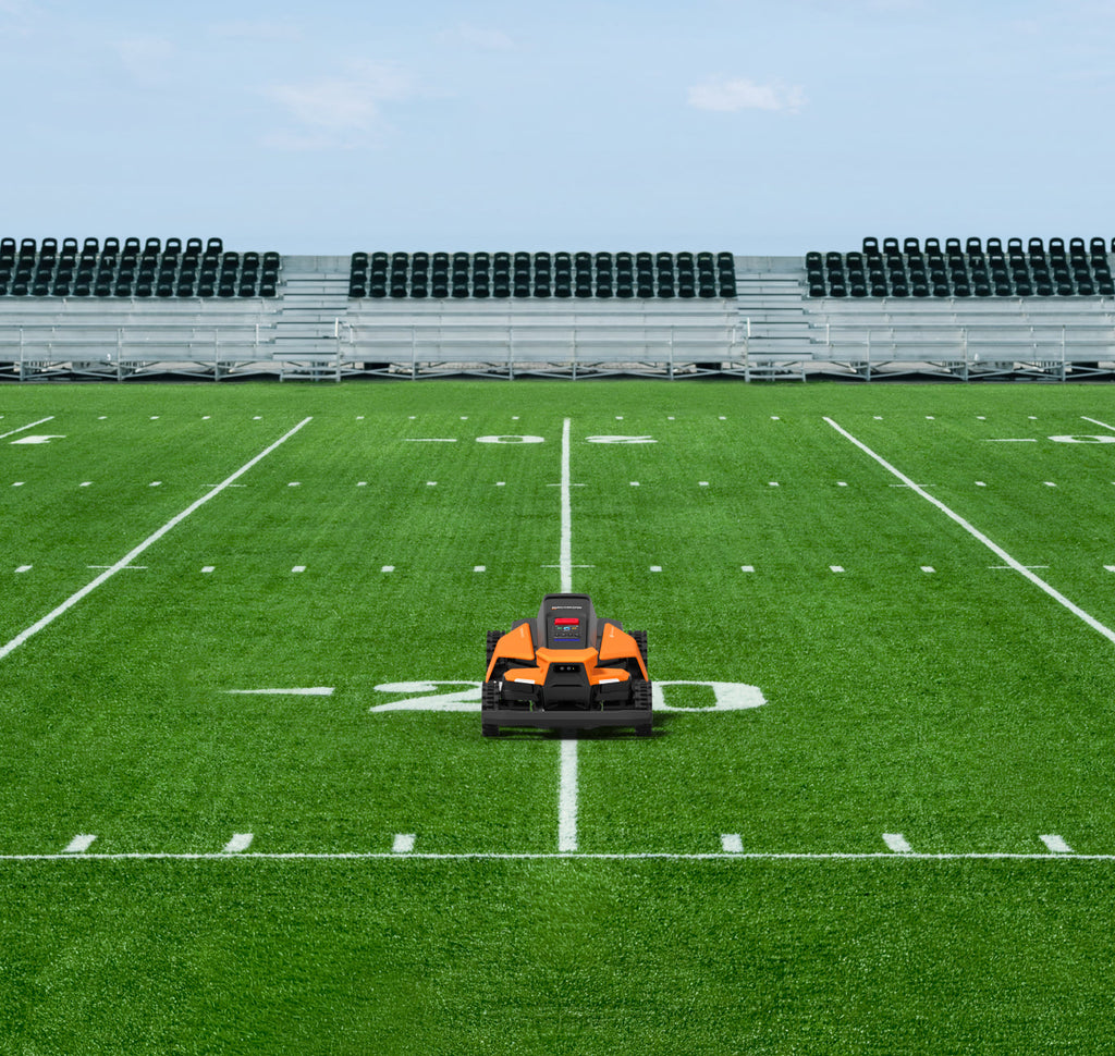 Navimow i110N robot lawn mower on a green football field.