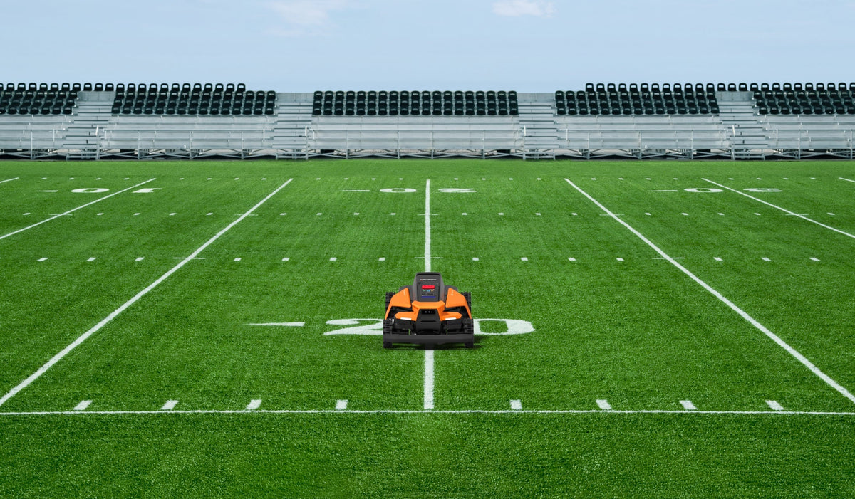 Navimow i110N robot lawn mower on a green football field.