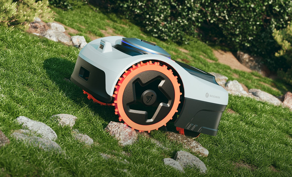 Segway Navimow i110N robot lawn mower traversing over some stones.