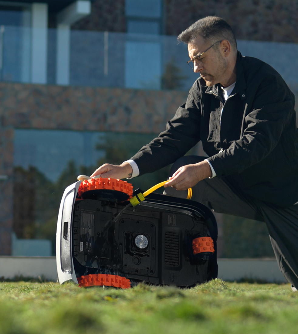 Man hosing down his Navimow i110N robot lawn mower outdoors.