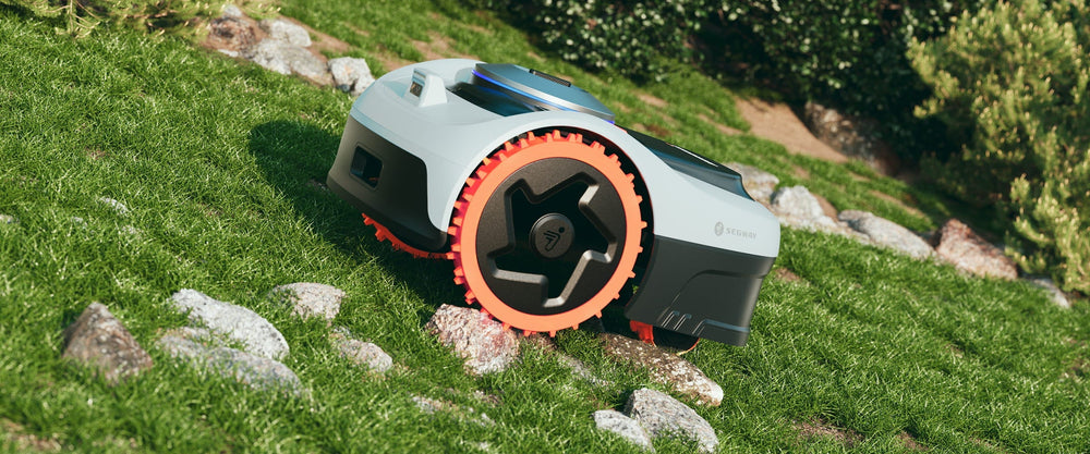 Segway Navimow i110N robot lawn mower on a grassy hill.